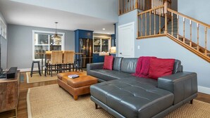 Ein Wohnzimmer mit einer Couch, einem Hocker und einer Treppe.