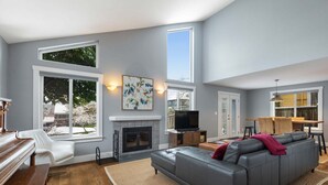 Ein Wohnzimmer mit Kamin, Sofa, Fernseher und Klavier.