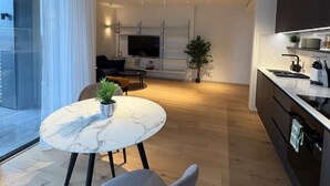 A modern kitchen with a dining area, a TV, and a plant.