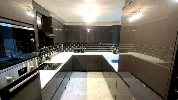Una cocina moderna con horno empotrado, microondas y cafetera sobre la encimera.