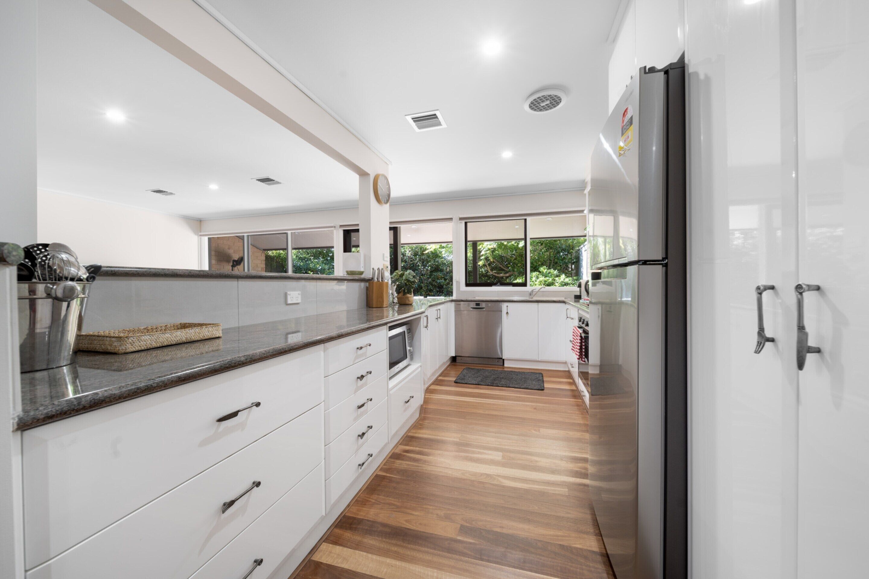 A modern kitchen with white cabinets, a granite countertop, and a stainless steel refrigerator.