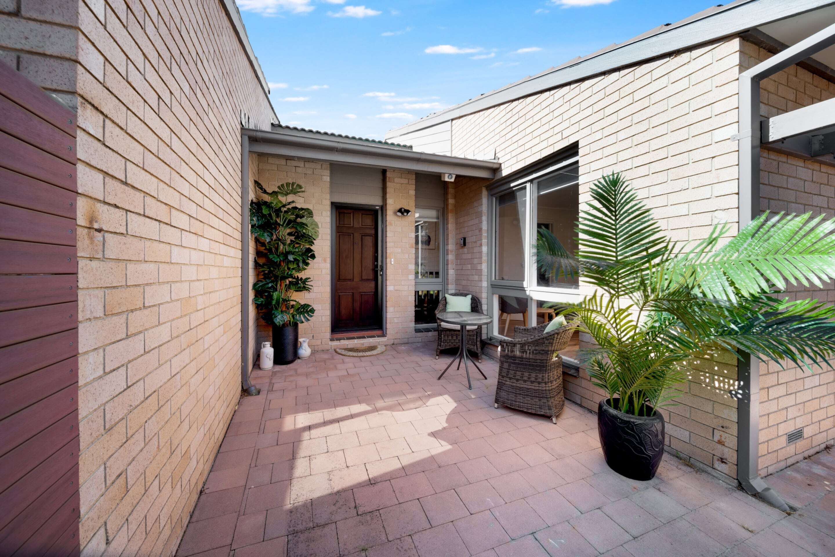 A brick house with a patio, a door, a window, and a potted plant.