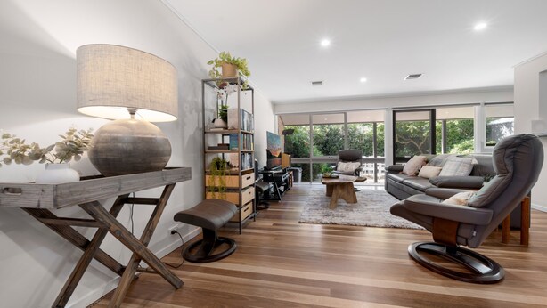 Un soggiorno moderno con parquet, un divano, un tavolino e una lampada.