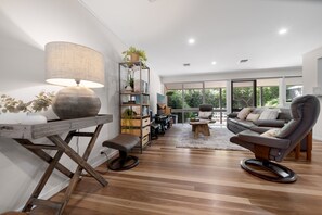 Uma sala de estar moderna com piso de madeira, um sofá, uma mesa de centro e um abajur.