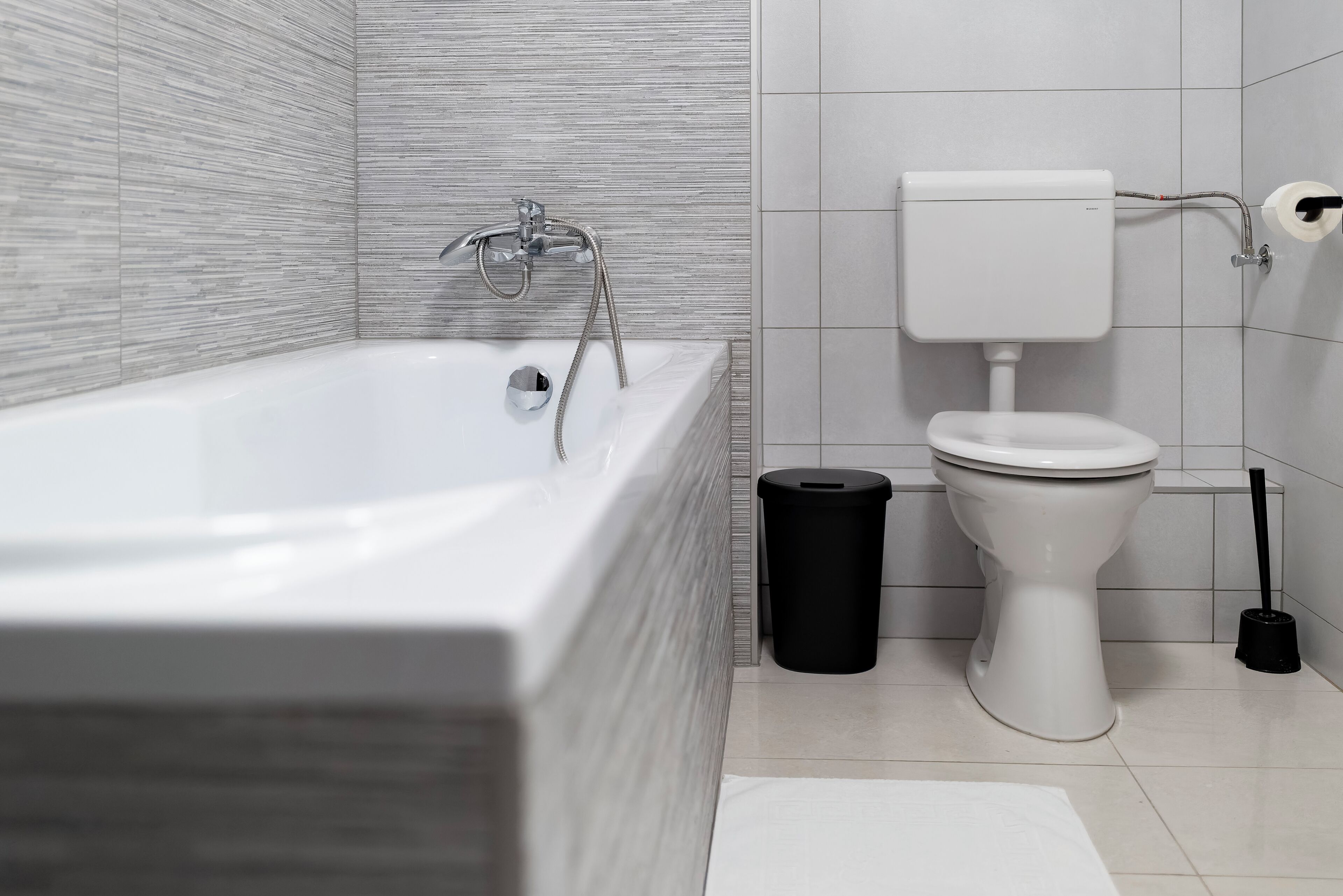 Um banheiro moderno com banheira, vaso sanitário e lixeira.