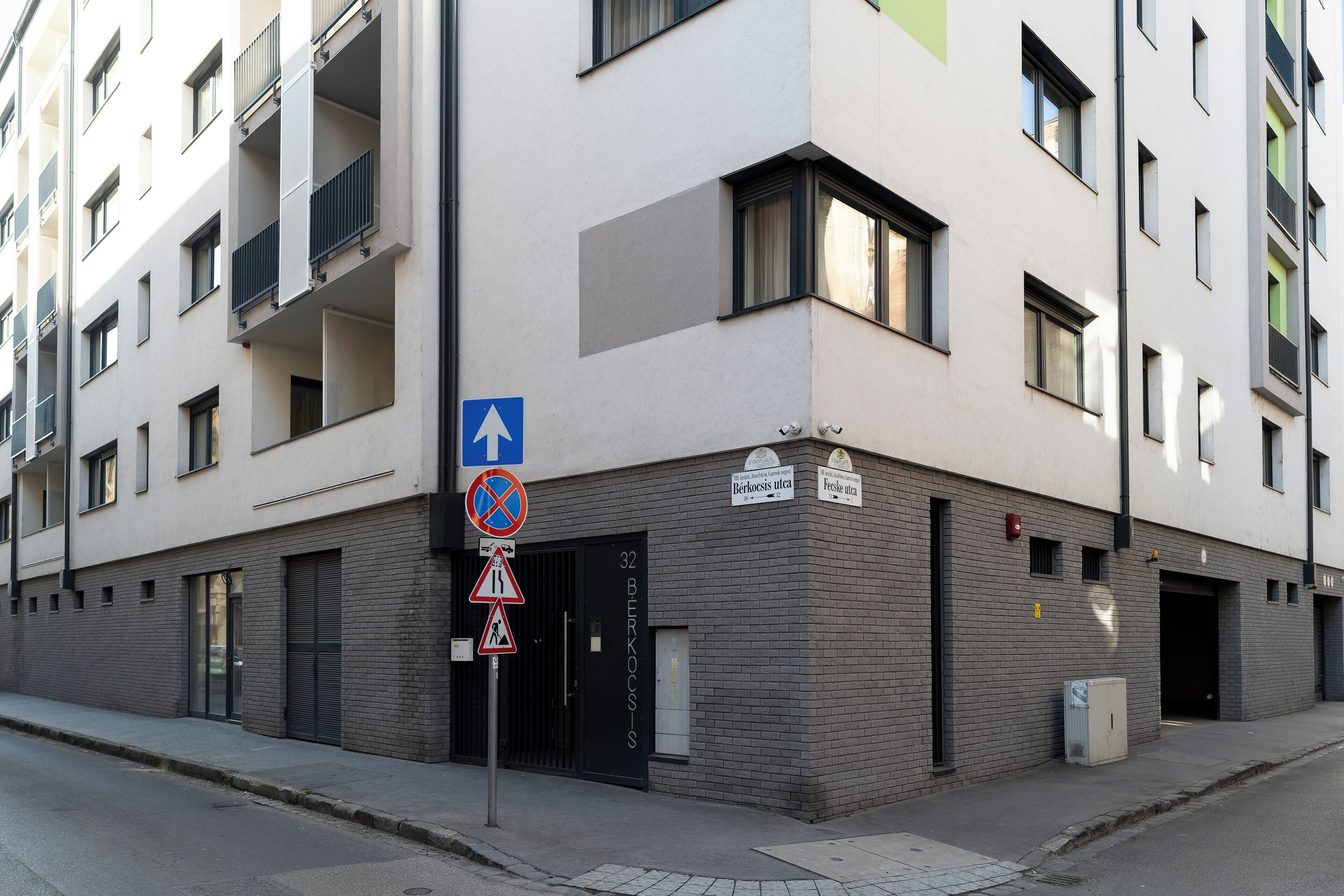 A multi-story building with a modern architectural style, featuring a mix of balconies and windows, and a visible entrance with a door marked '32 BERKOSIS.'
