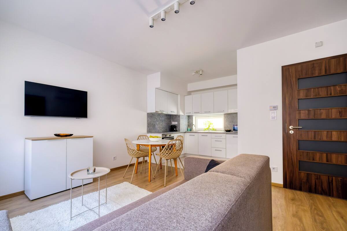 A modern living space with a dining area, kitchenette, and a large wooden door.