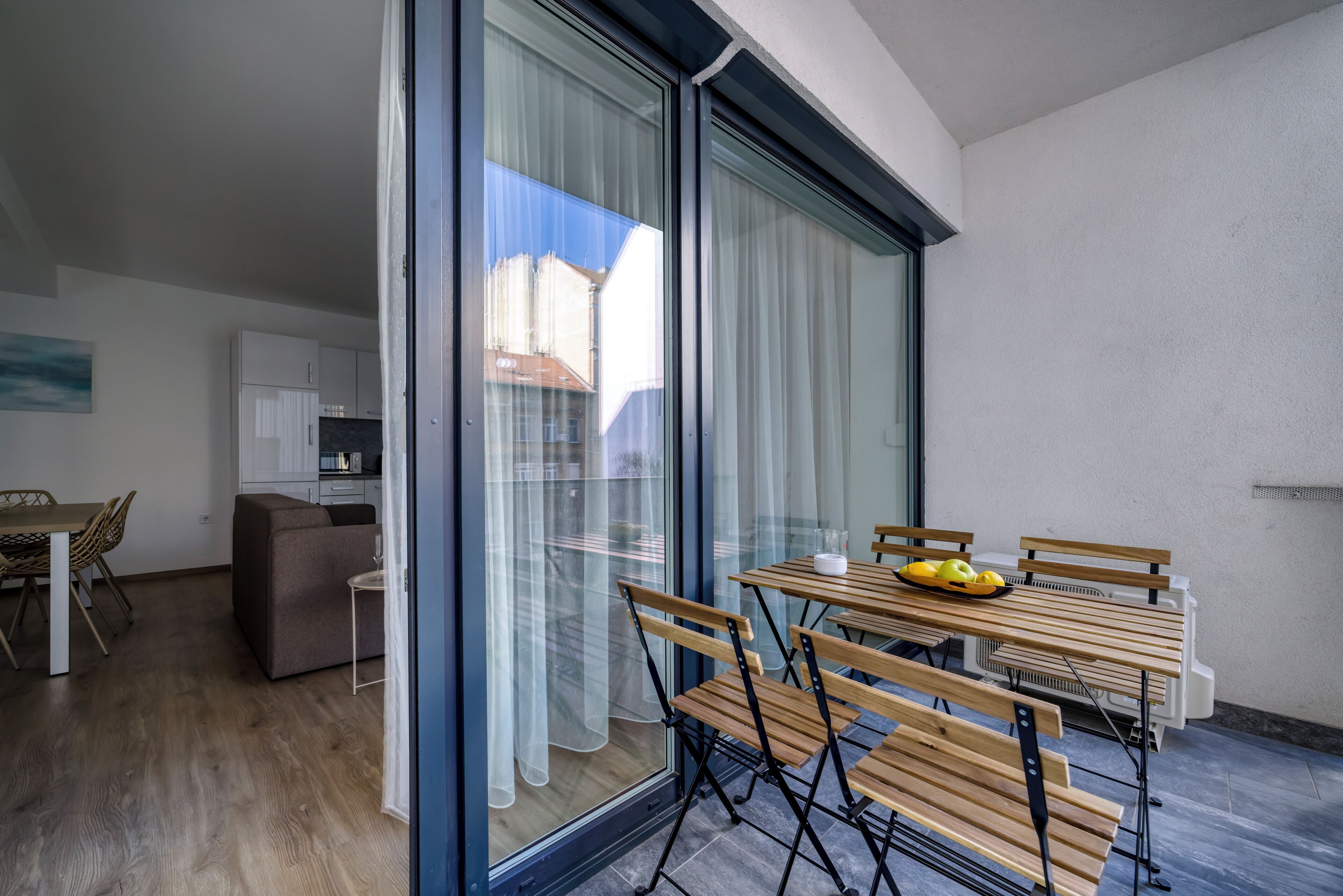 A modern living room with a dining area, large sliding glass doors, and a view of the outside.