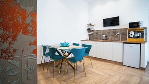 Een moderne keuken met witte kastjes, een eettafel met blauwe stoelen en een kleine koelkast.