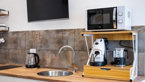 Een keuken met een magnetron, koffiezetapparaat en blender op een houten aanrecht.