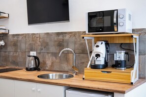 Eine Küche mit Mikrowelle, Kaffeemaschine und Mixer auf einer Holzausziehtischplatte.