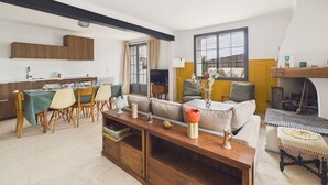 A modern living room with a sofa, a dining area with chairs and a table, and a kitchen with wooden cabinets. - 700 m from the beach, House for 8, garden (L'Epine)