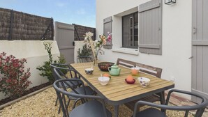 A patio with a table set for tea, surrounded by chairs, and a flower vase. - 700 m from the beach, House for 8, garden (L'Epine)