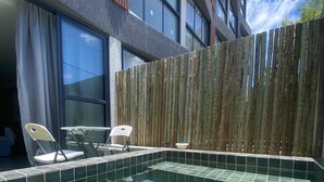 A swimming pool with tiled flooring, a wooden fence, and a building with large windows in the background. - Nawa 01 com piscina privativa by LP (Tamandaré)