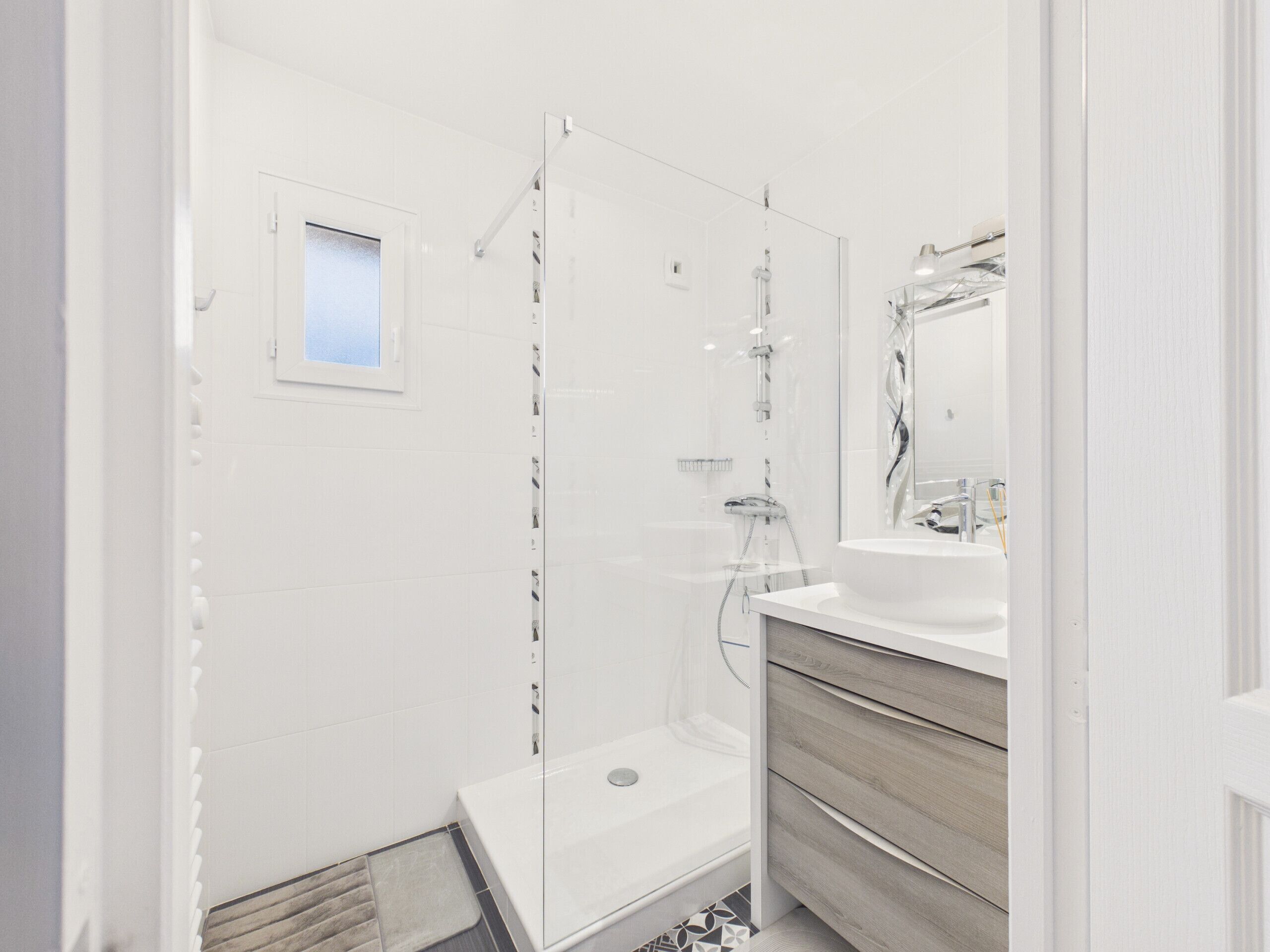 A modern bathroom with a glass-enclosed shower, a sink, and a vanity.
