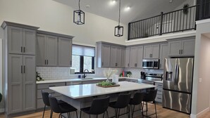 Una cocina moderna con armarios grises, un refrigerador de acero inoxidable y una isla central con taburetes de bar.