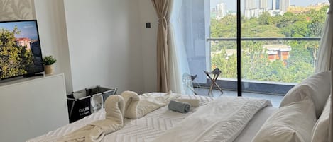 A hotel room with a large bed, a view of the city, and a television on the wall.