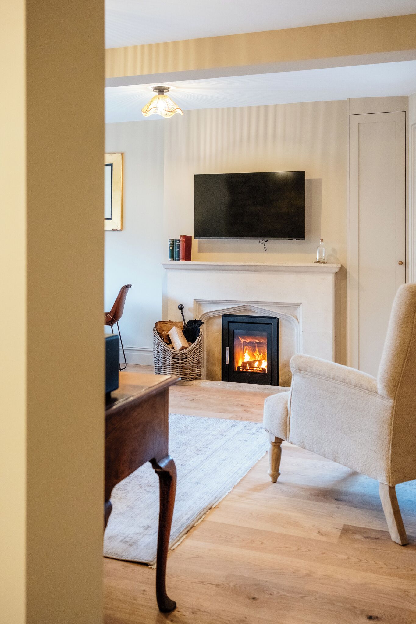 Een woonkamer met een open haard, een televisie erboven en een comfortabele fauteuil.