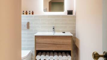 A bathroom with a white sink, a mirror, and a towel rack.