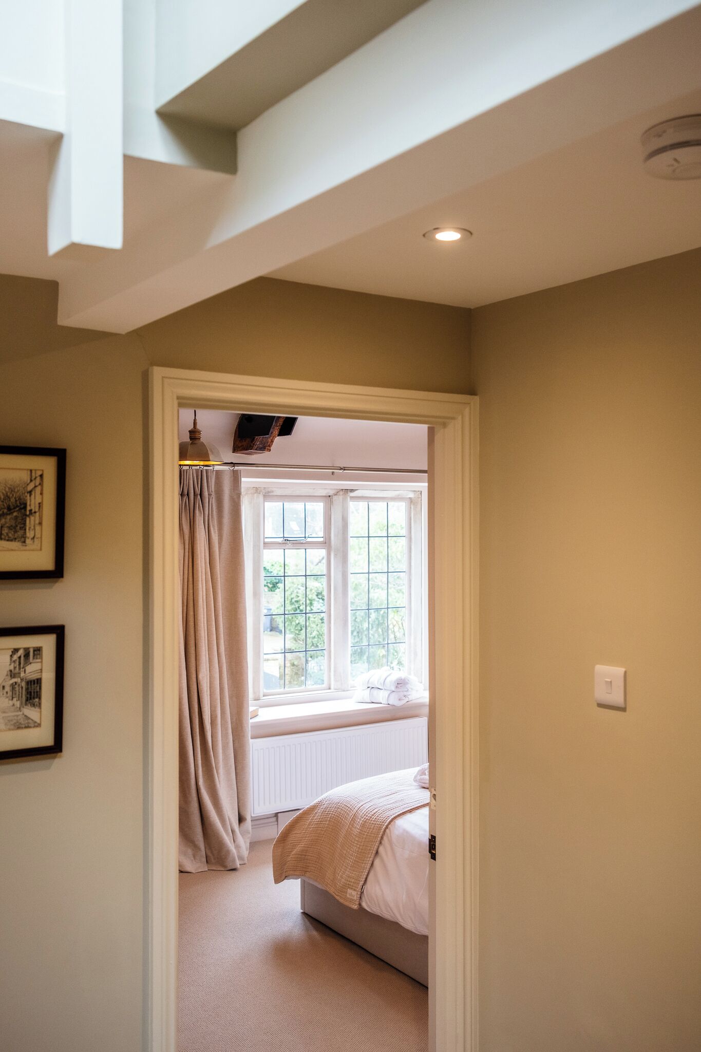 Une chambre avec une fenêtre, un lit, un radiateur et un luminaire au plafond.