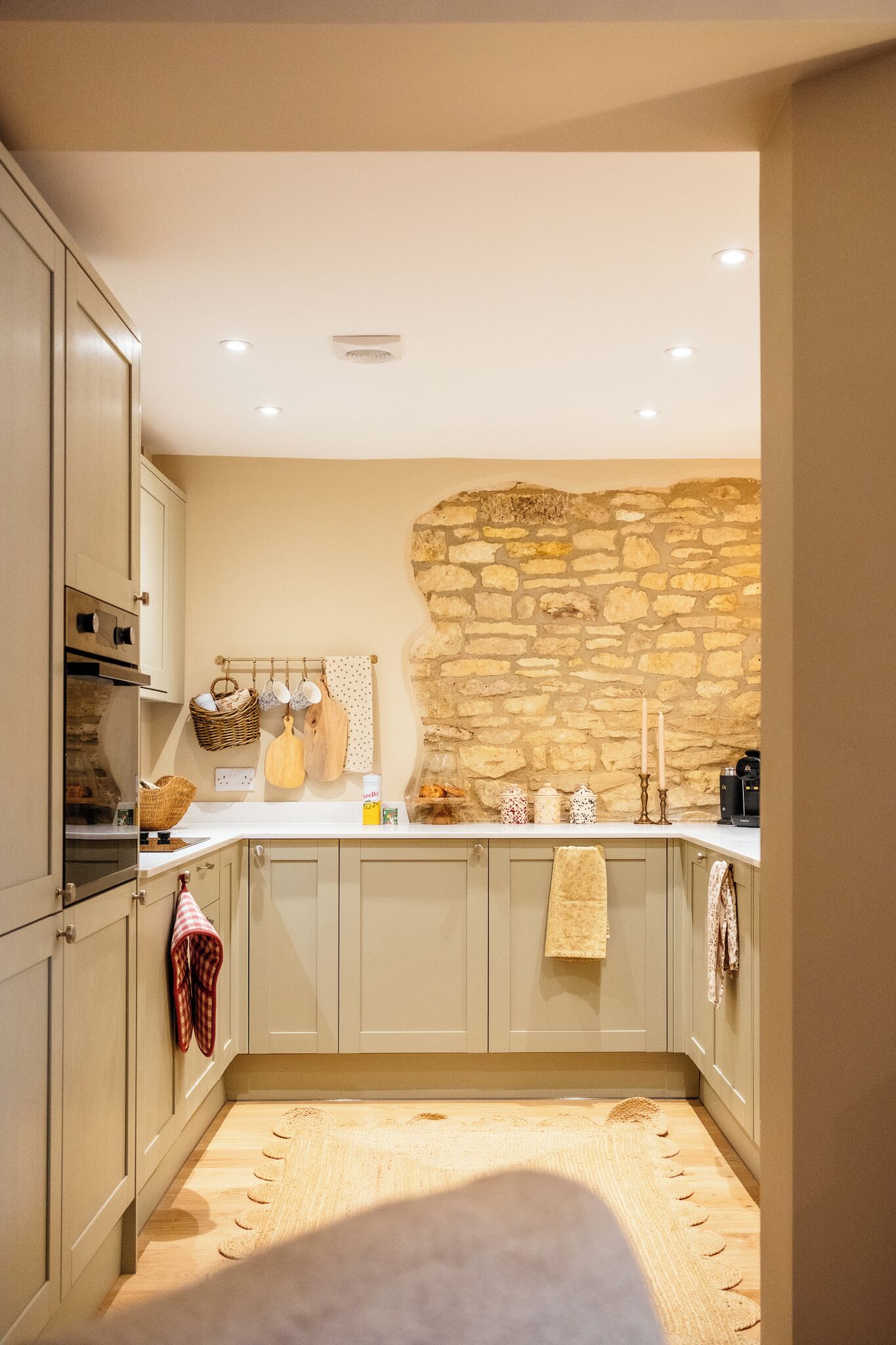 Een keuken met een stenen muur, houten keukenkastjes en een aanrecht met keukengerei.