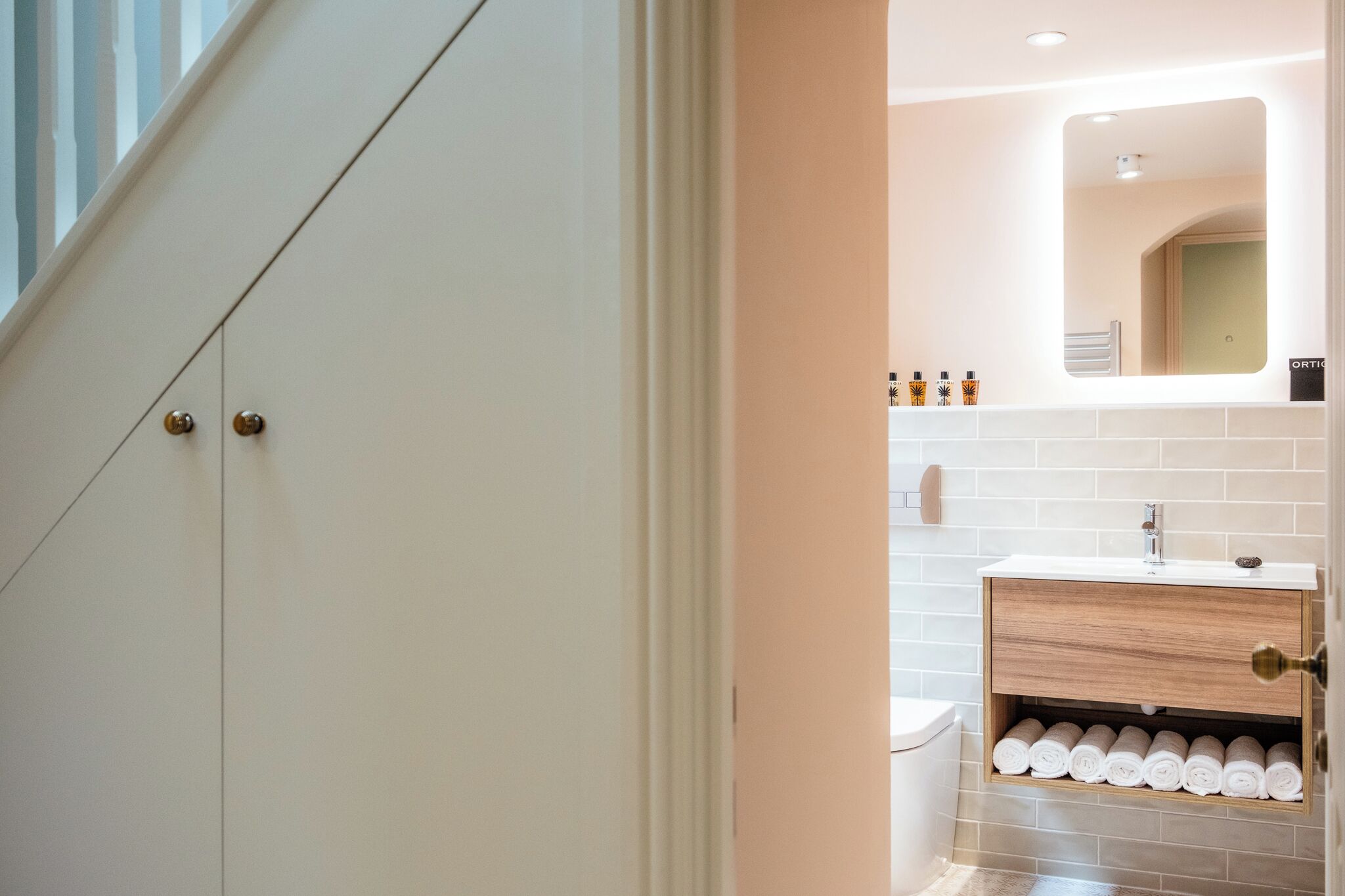Un bagno moderno con un mobile lavabo bianco, uno specchio e asciugamani ordinatamente piegati.