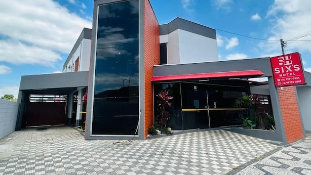 Un hôtel moderne avec une enseigne rouge et blanche, une entrée abritée et une allée pavée.
