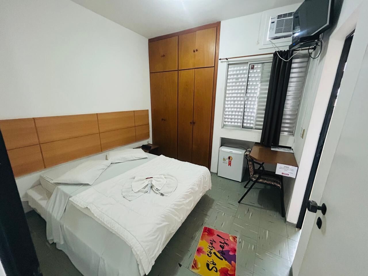 Een slaapkamer met een bed, kledingkast, bureau en een airconditioning.
