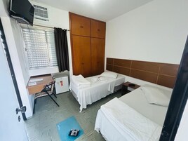 Habitación de hotel con dos camas, un escritorio, un armario y una ventana con cortinas.