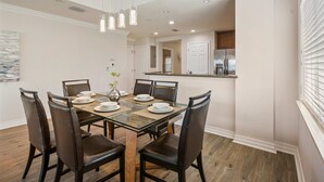 Un coin repas comprenant une table en verre, six chaises et un vase avec une plante.
