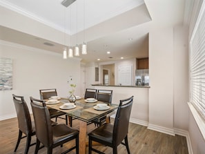 A dining area with a glass table, six chairs, and a vase with a plant. - New! Epic Sunset Escape at Reunion Resort (Kissimmee)