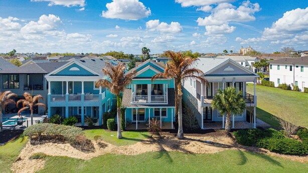 A beachfront property with multiple houses, a swimming pool, and palm trees. - New! Luxury Reunion Villa | Theater • Pool • Game Room (Kissimmee)