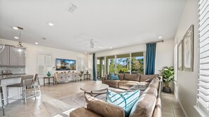 A spacious living area with a large sofa, a coffee table, and a kitchen in the background. - Epic Playhouse Getaway - Castle & Superhero Bunks, Theater, Private Pool, No Rear Neighbors (Four Corners)