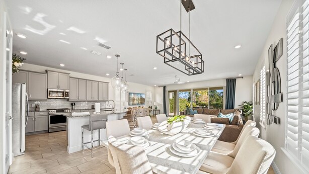 A modern kitchen with a central island, a dining area with a long table, and a living area with a sofa and large windows. - Epic Playhouse Getaway - Castle & Superhero Bunks, Theater, Private Pool, No Rear Neighbors (Four Corners)