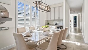 A modern kitchen with white cabinets, a marble countertop, and a hanging light fixture. - Epic Playhouse Getaway - Castle & Superhero Bunks, Theater, Private Pool, No Rear Neighbors (Four Corners)