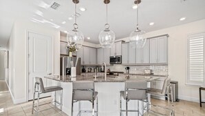 A modern kitchen with a central island, bar stools, stainless steel appliances, and pendant lighting. - Epic Playhouse Getaway - Castle & Superhero Bunks, Theater, Private Pool, No Rear Neighbors (Four Corners)