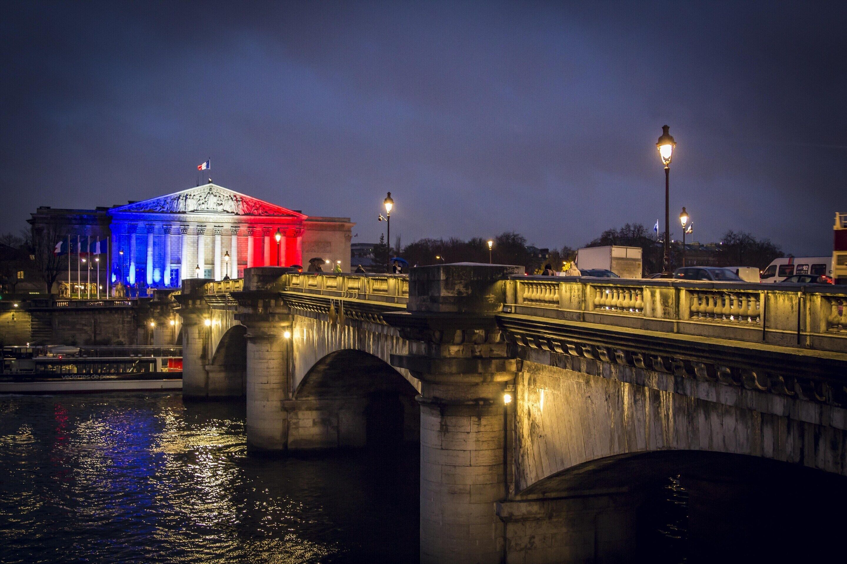 Un puente con arcos de piedra y un edificio con columnas iluminadas.