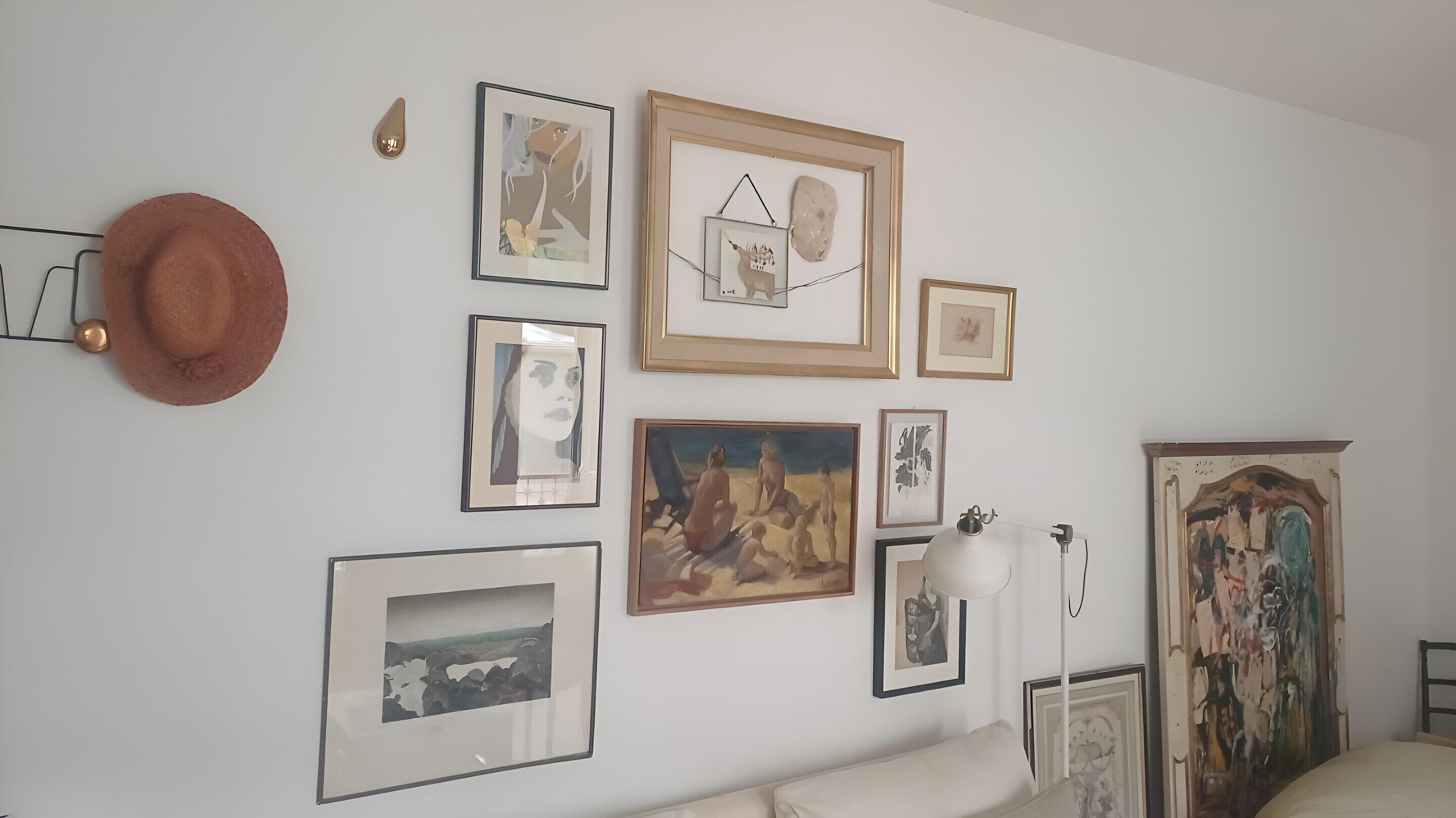 Une pièce comprenant un lit, une lampe fixée au mur et divers tableaux encadrés.