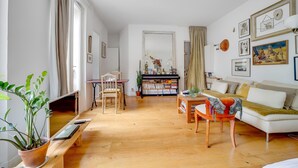 Un salon avec un canapé, une table basse, un téléviseur, une bibliothèque et une plante en pot.