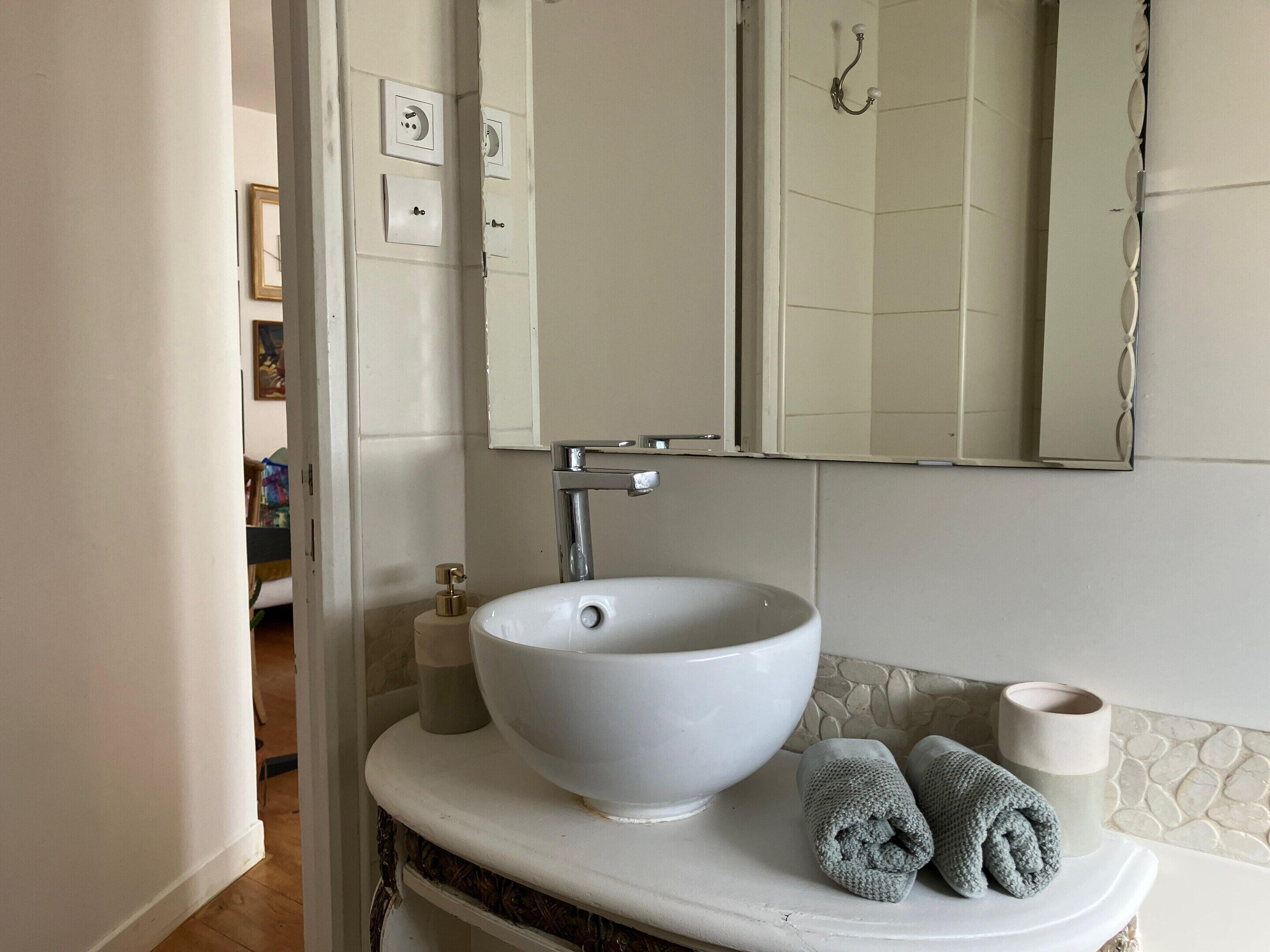 A bathroom with a white sink, a mirror, and a towel.
