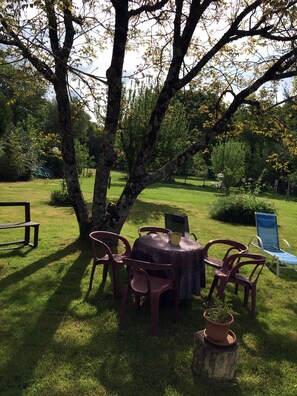 A round table with chairs and a bench in a grassy outdoor area with trees. - Les Closeries du Golfe (Theix-Noyalo)