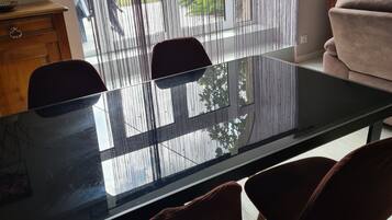 Un comedor moderno con una mesa de vidrio, dos sillas, un mueble de madera y un sofá.
