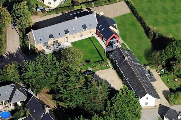 An aerial view of a residential area with a large house featuring a sloped roof, a swimming pool, and a well-maintained lawn. - Les Closeries du Golfe (Theix-Noyalo)