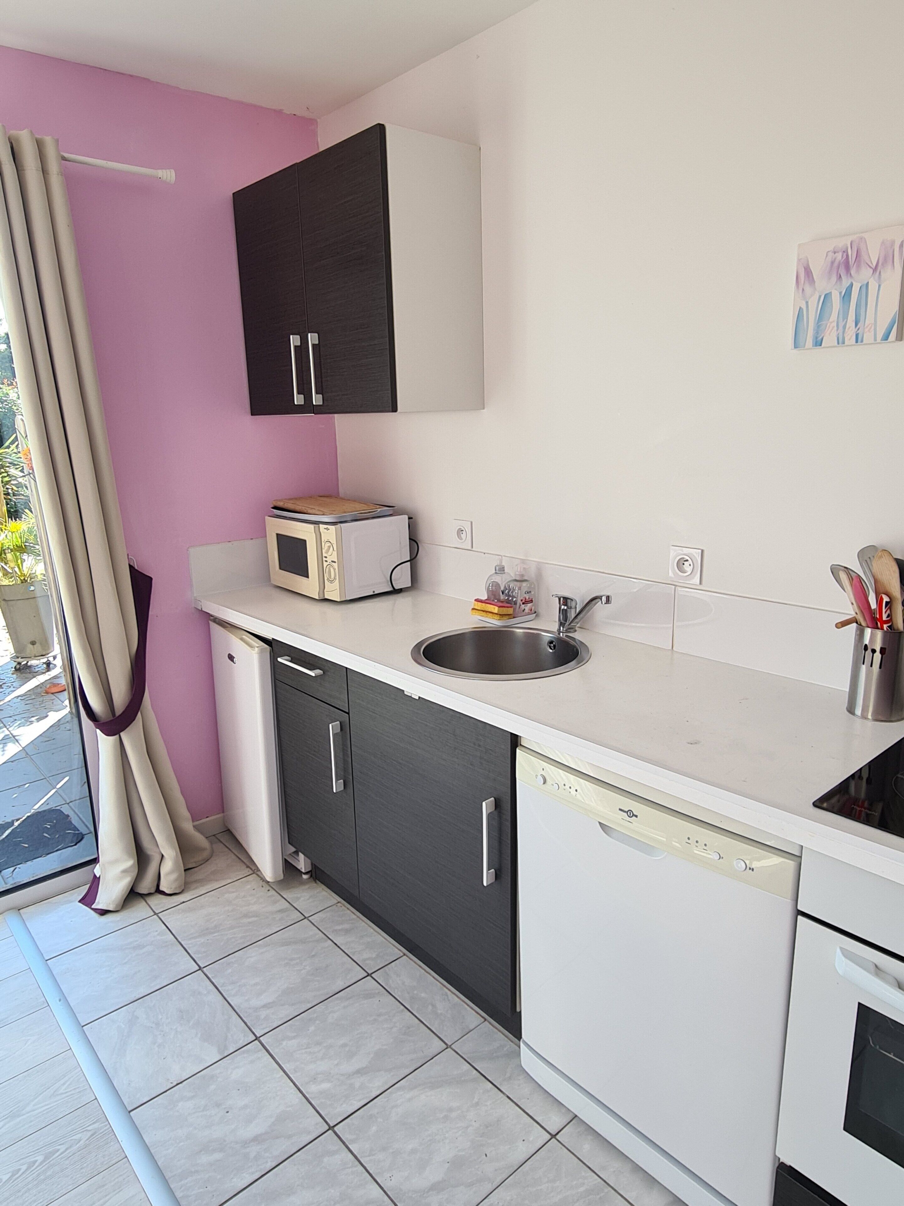 A compact kitchen with a microwave, sink, and dishwasher.