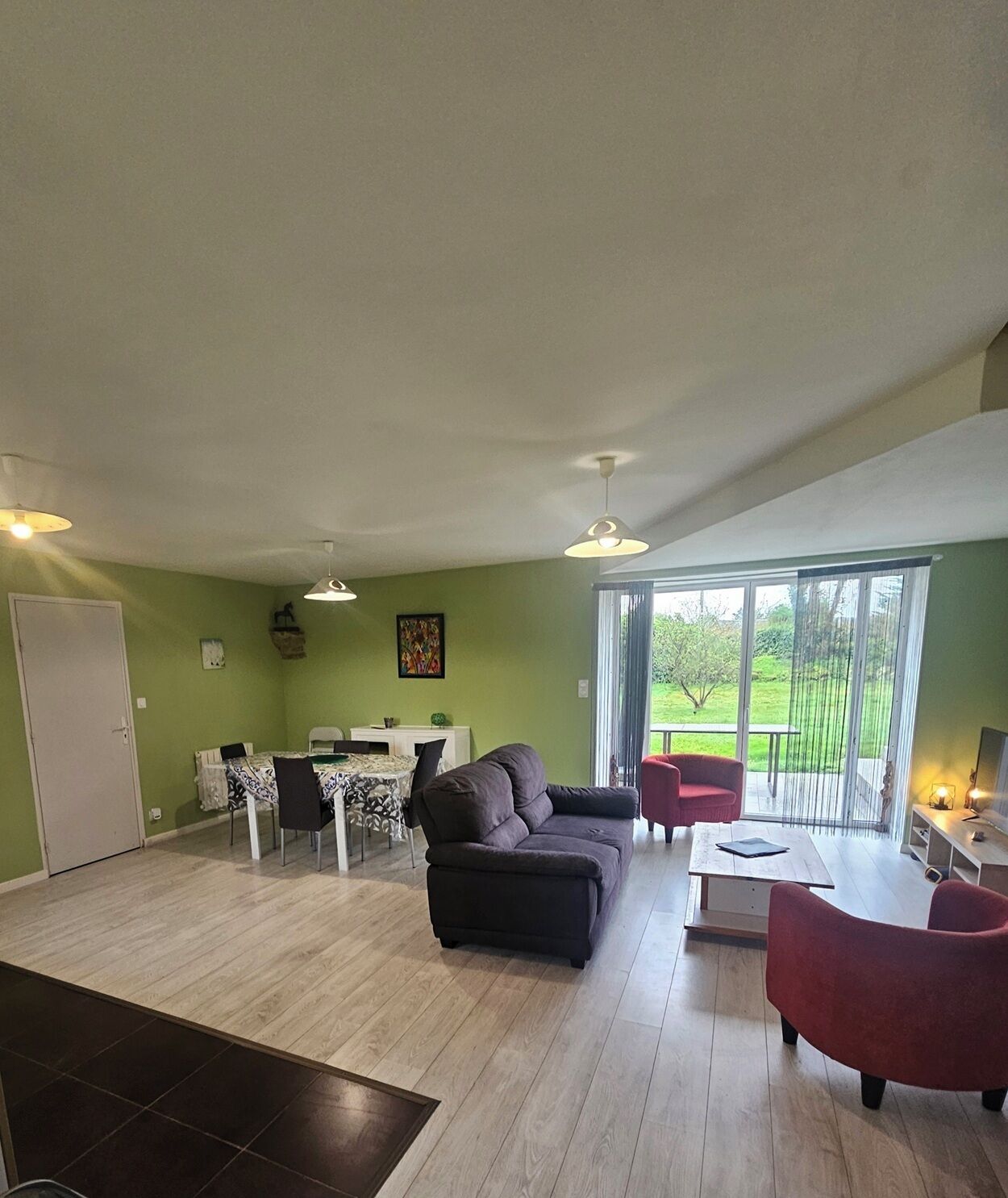Un vaste espace de vie comprenant un canapé, une table à manger, des chaises et un balcon avec vue.