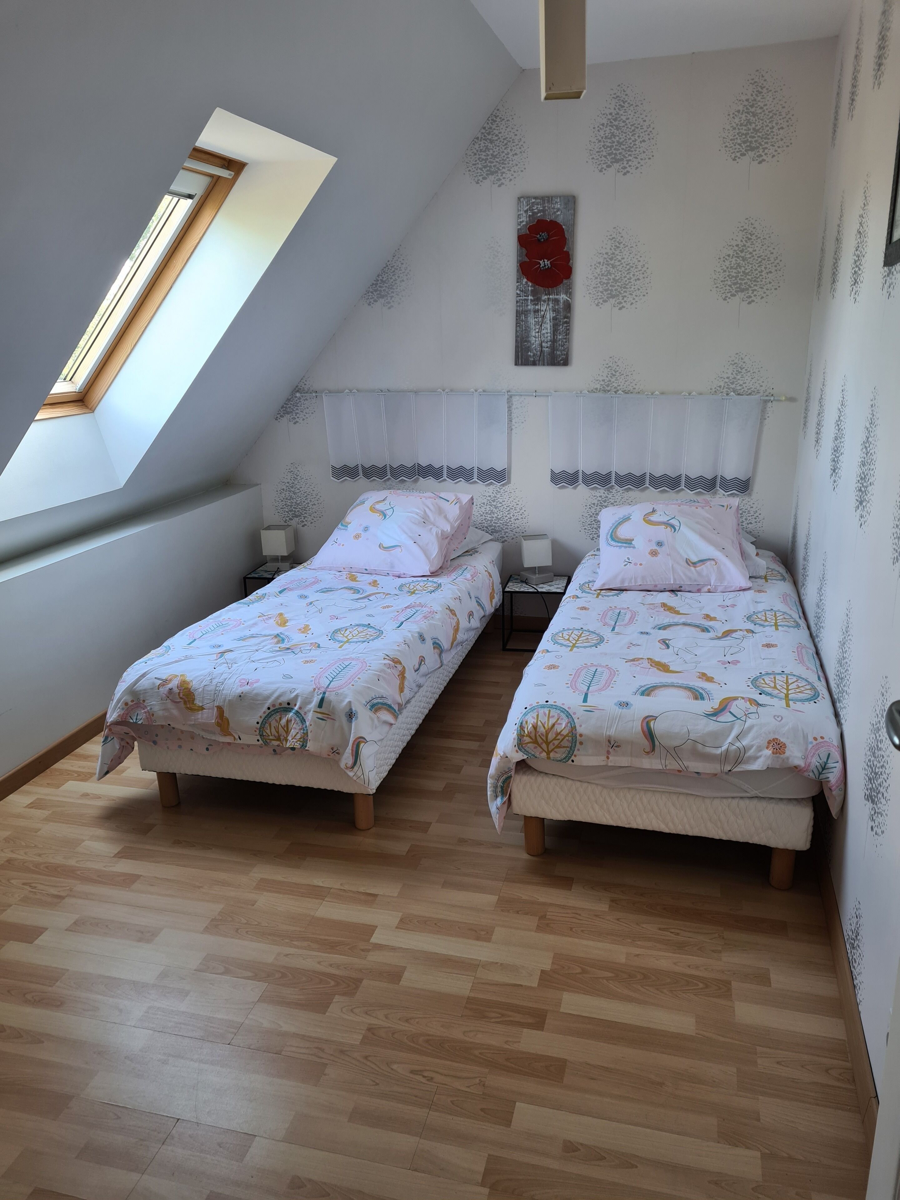 Un dormitorio con dos camas, un tragaluz y un detalle decorativo en la pared.