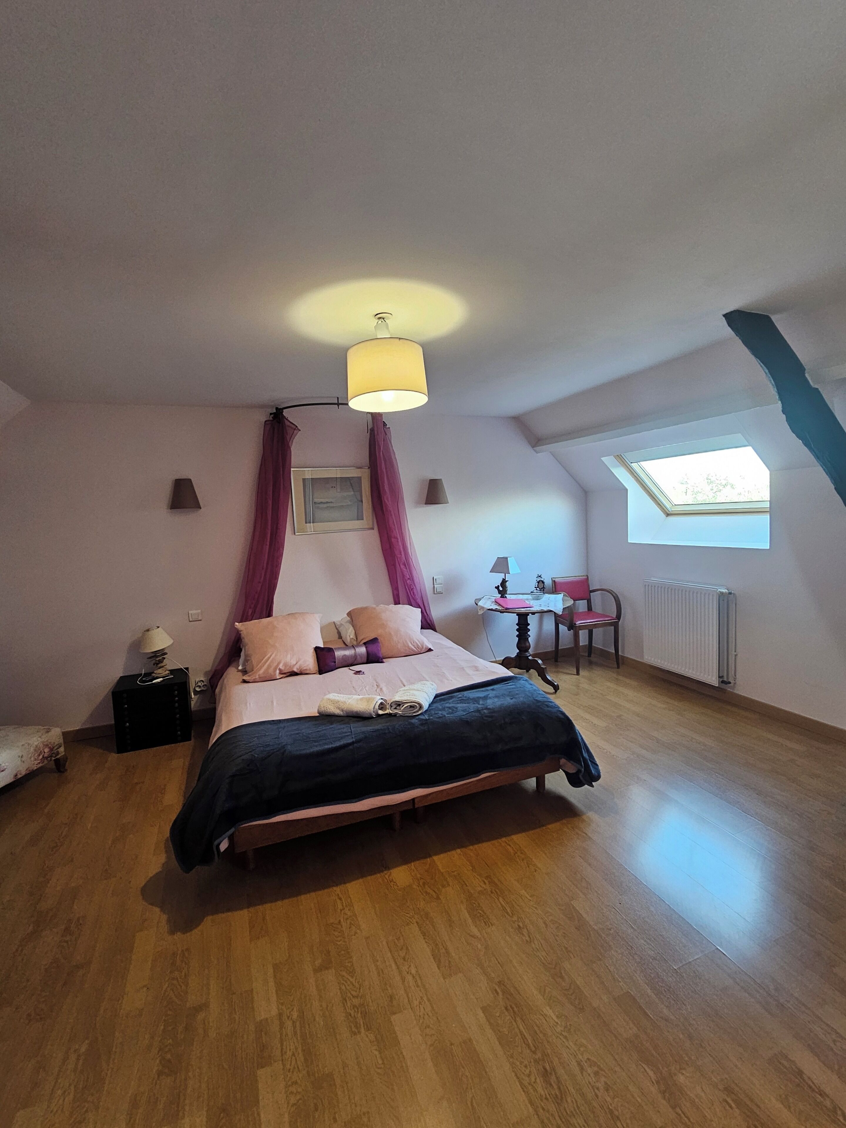 A bedroom with a bed, a window, a lamp, and a radiator.