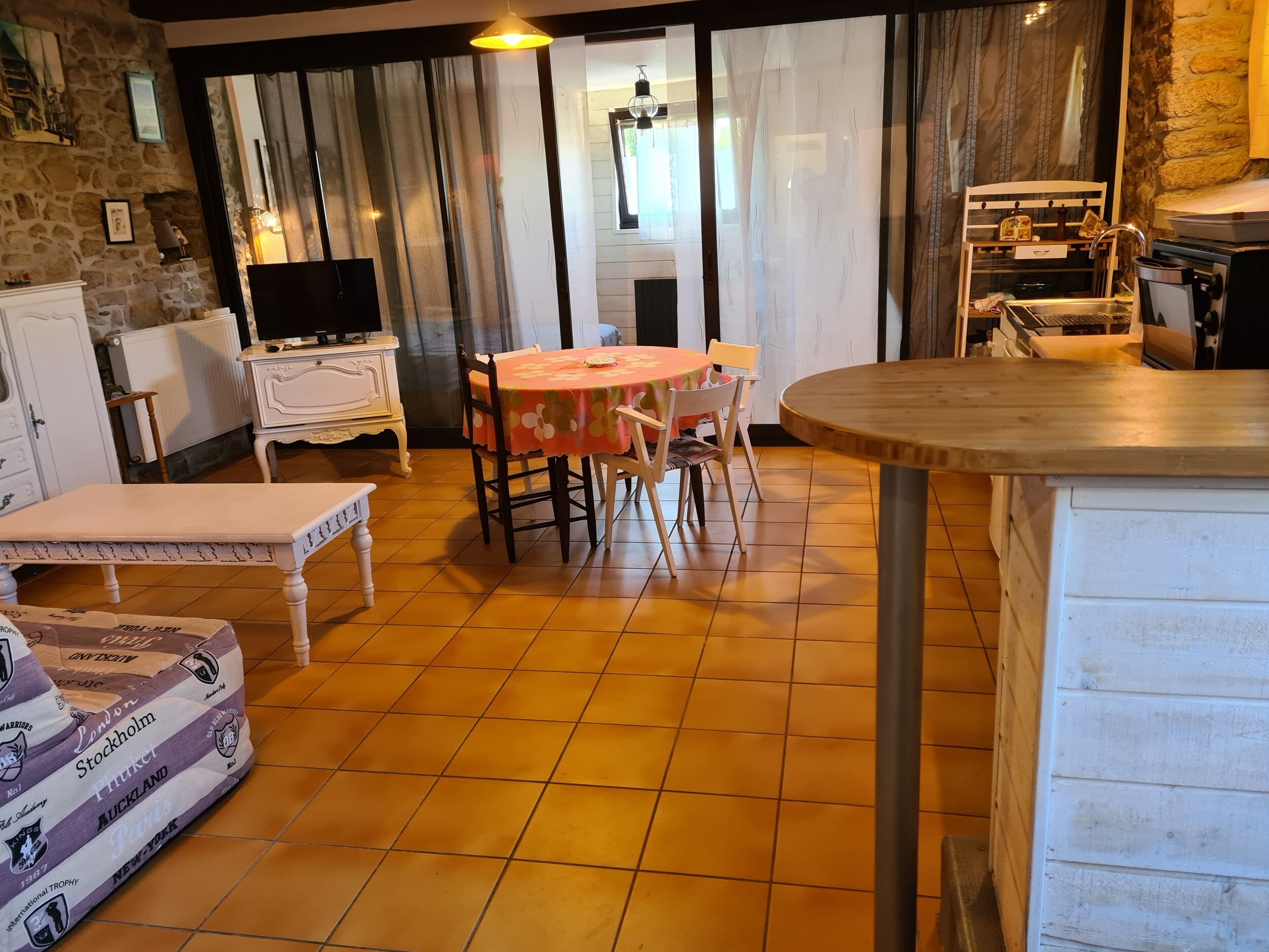A dining area with a table, chairs, a bench, and a kitchen area with appliances.