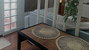 A room with a wooden table, two woven placemats, a white sofa, and hanging plants. - Nice house with terrace (San Cristóbal De La Laguna)