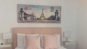 A bedroom with a bed, two bedside lamps, a headboard, and a wall-mounted painting of the Eiffel Tower. - Nice house with terrace (San Cristóbal De La Laguna)